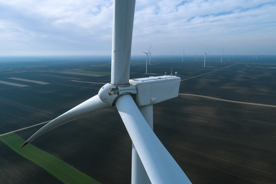 aerial view of a wind turbine with multiple wind turbines in the background on an open landscape